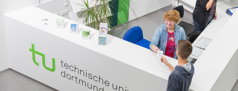 Studierendenberatung Ein Student gibt seine Wartenummer bei der Studienberatung ab.
